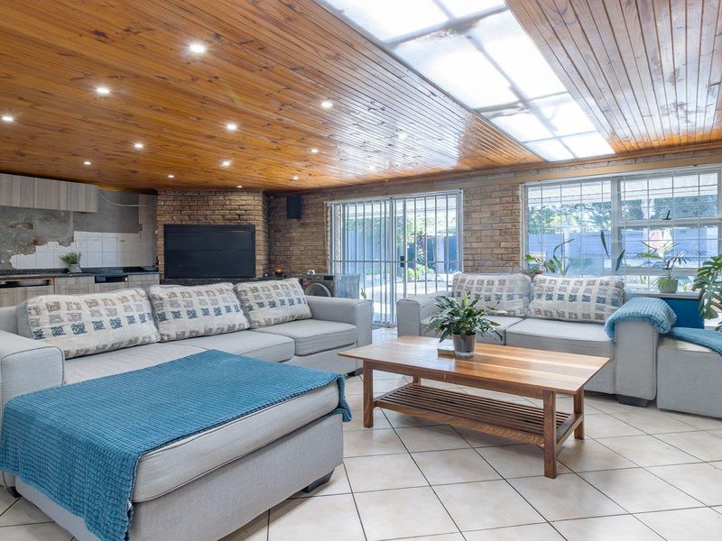 Spacious open-plan living area featuring exposed brick walls, a timber-clad ceiling with skylight, and an integrated kitchen space with granite countertops.