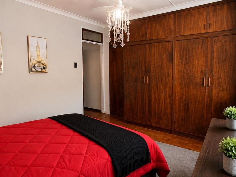 A bedroom featuring extensive built-in wooden cabinetry, a ceiling fan, and neutral wall finishes.