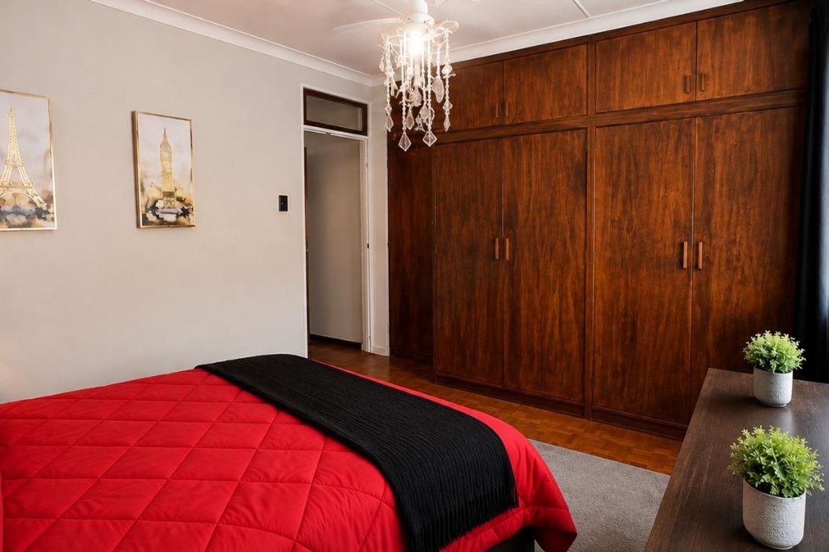 A bedroom featuring extensive built-in wooden cabinetry, a ceiling fan, and neutral wall finishes.