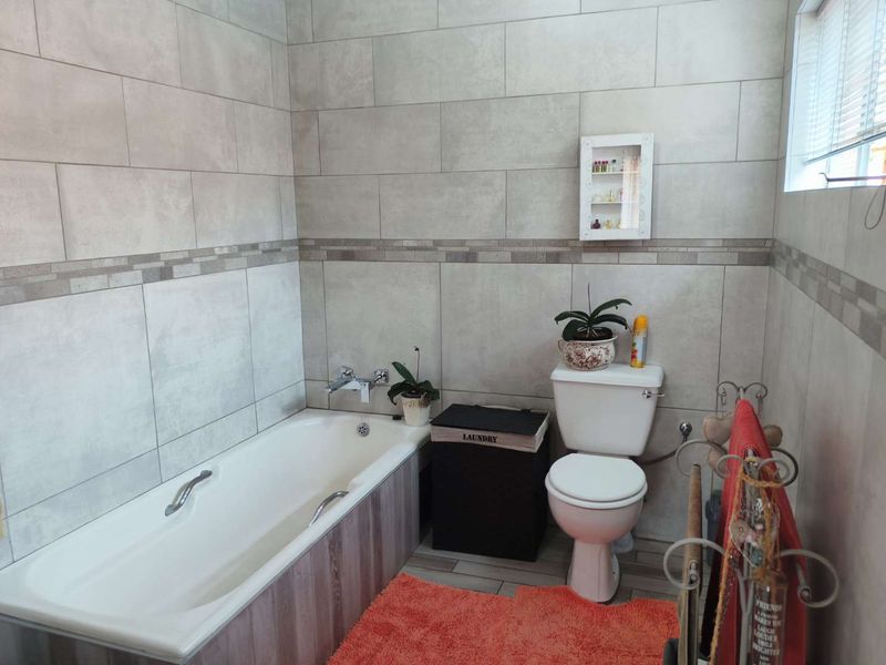 A functional bathroom featuring neutral wall tiling, a standard bathtub, and a toilet, offering a clean and well-maintained space.