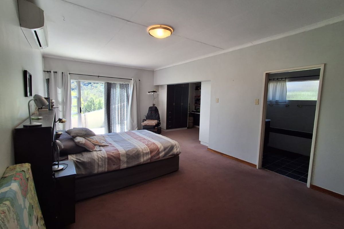 Spacious bedroom featuring built-in cupboards, an en-suite bathroom, and sliding glass doors leading to an outdoor area with air conditioning.