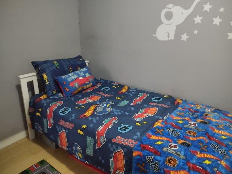 A functional bedroom featuring laminate flooring and neutral wall paint, currently styled as a child's room.