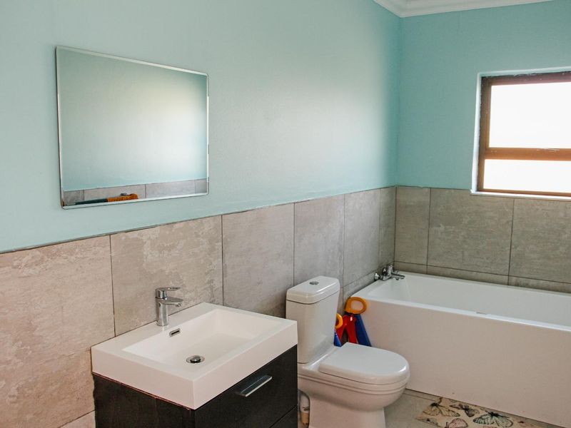 A functional bathroom featuring a modern vanity with basin, a standard toilet, and a bathtub with tiled wall finishes.