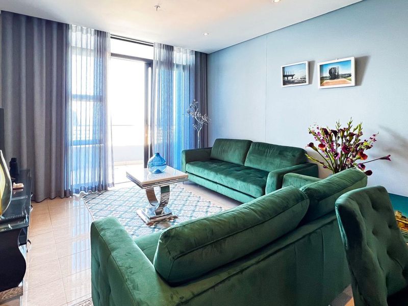 A well-maintained living room featuring tiled flooring, recessed lighting, and a large sliding glass door providing access to the balcony.