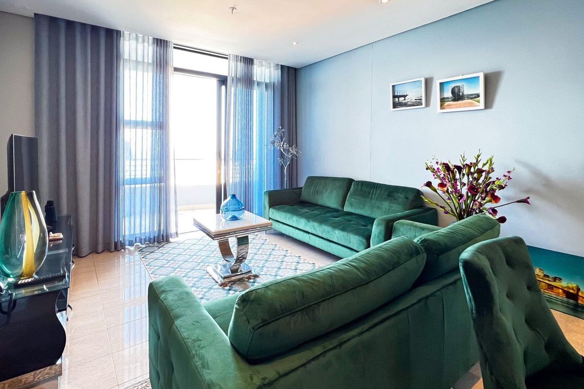 A well-maintained living room featuring tiled flooring, recessed lighting, and a large sliding glass door providing access to the balcony.