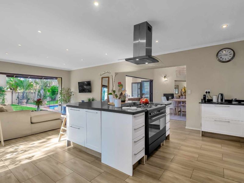 Spacious open-plan kitchen and living area featuring a central island, modern gas hob, extractor fan, and large sliding doors opening to the garden.