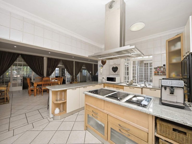 Spacious open-plan kitchen featuring a central island with built-in hob, granite countertops, and ample cabinetry, seamlessly flowing into the adjacent dining area.