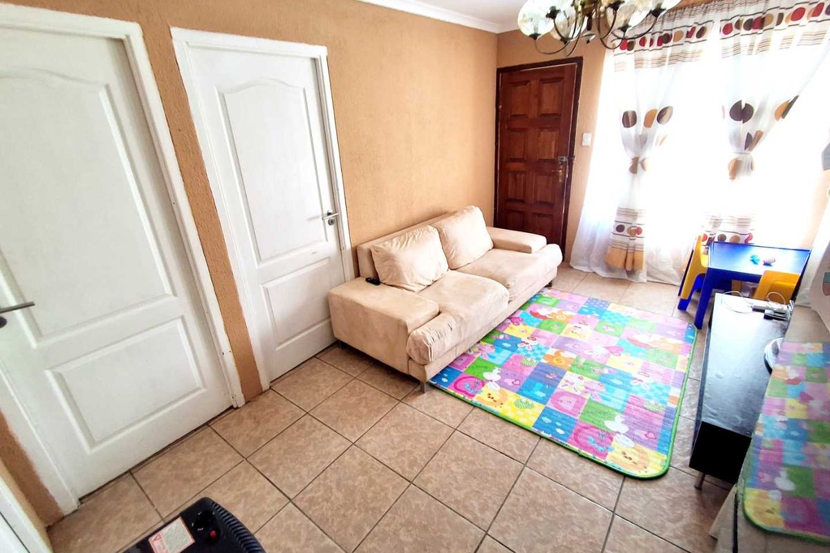 A living room featuring tiled flooring, neutral wall finishes, and multiple interior doors, providing a functional and accessible living space.
