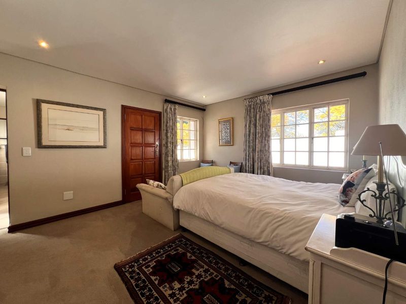 A well-lit bedroom featuring carpeted flooring, recessed downlighting, and classic multi-pane windows, offering a comfortable and functional living space.