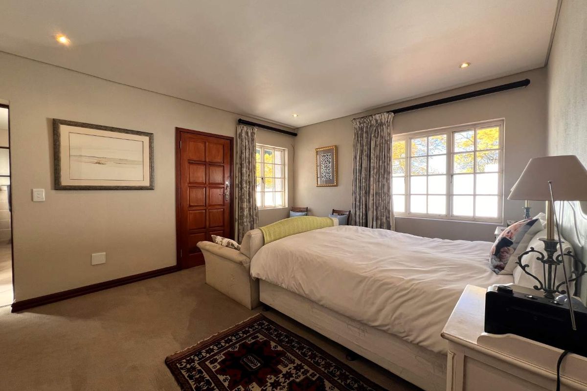 A well-lit bedroom featuring carpeted flooring, recessed downlighting, and classic multi-pane windows, offering a comfortable and functional living space.