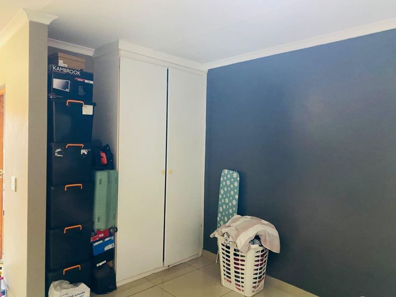 A bedroom featuring a built-in wardrobe, tiled flooring, and a dark accent wall, providing a functional space with storage potential.