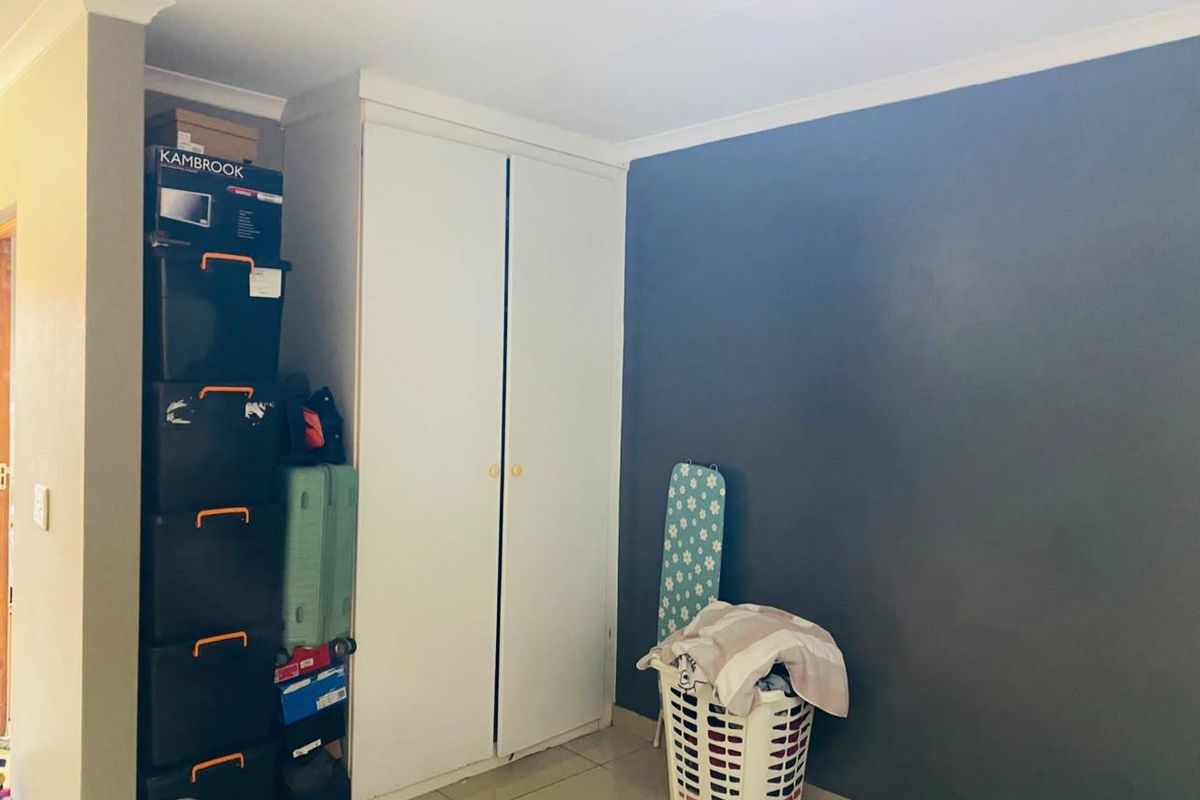 A bedroom featuring a built-in wardrobe, tiled flooring, and a dark accent wall, providing a functional space with storage potential.