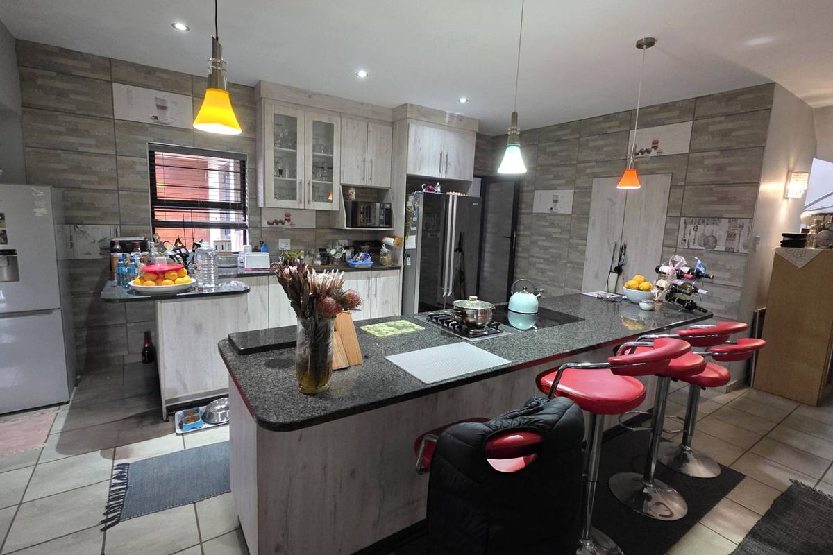 Spacious kitchen featuring a large central island with granite countertops, built-in cabinetry, and modern pendant lighting, offering a functional and contemporary cooking space.