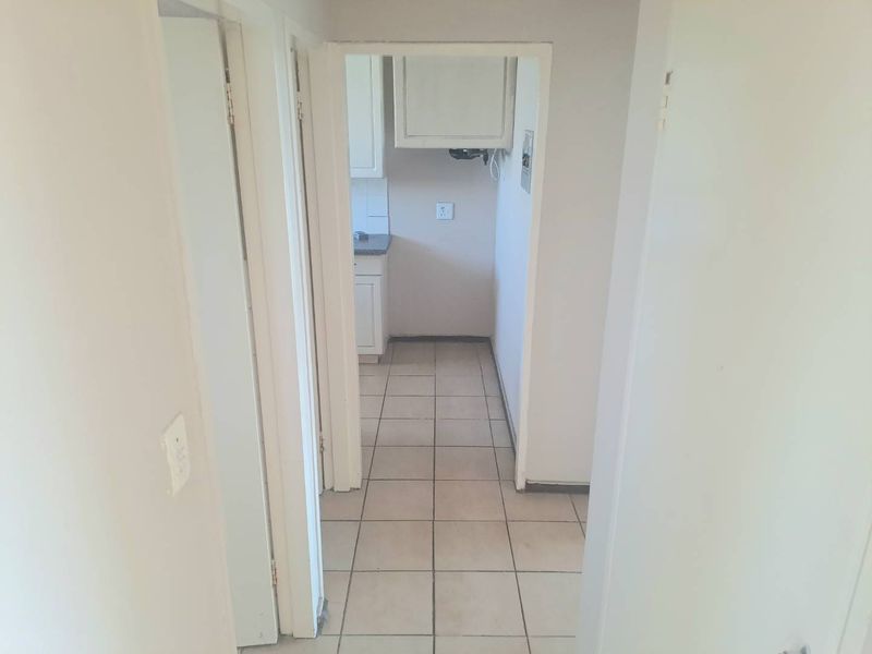 A functional, empty scullery area featuring tiled flooring and built-in cabinetry, providing a practical space for laundry or additional kitchen preparation.