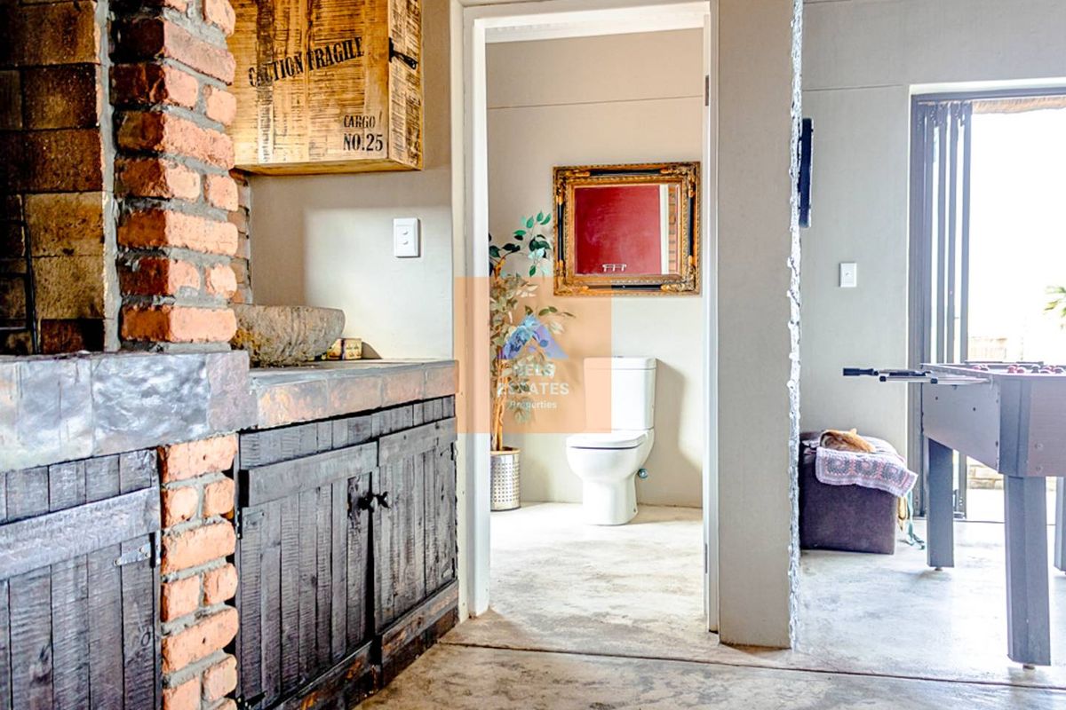Living area featuring an exposed brick fireplace, built-in cabinetry, and concrete flooring, with an adjacent bathroom visible through the doorway.
