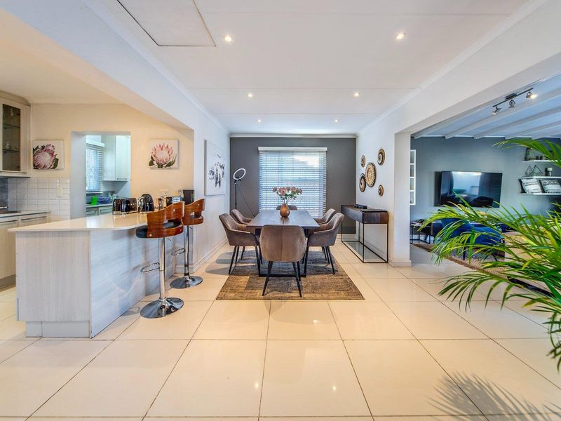 Spacious open-plan living and dining area featuring modern tiled flooring, recessed lighting, and a functional kitchen island with breakfast bar seating.