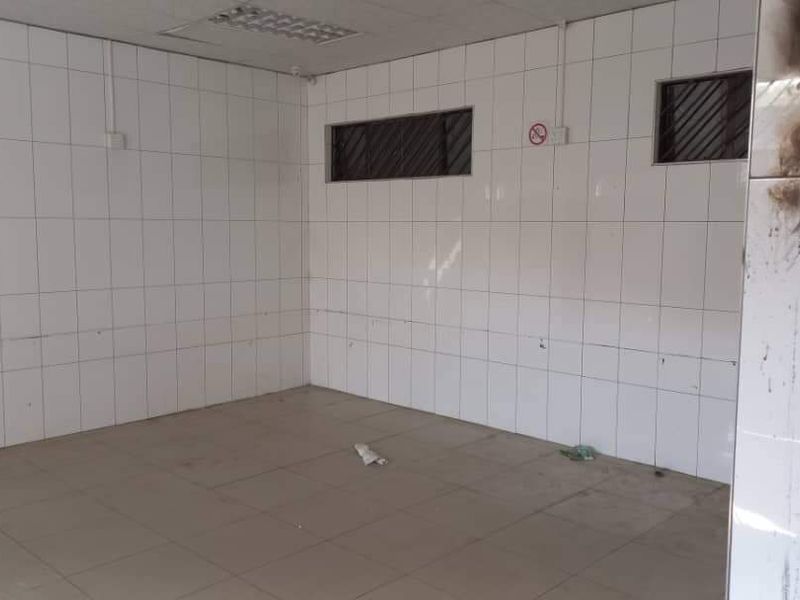 An empty industrial utility space featuring fully tiled walls and floors, recessed lighting, and high-level windows, currently showing signs of fire damage.
