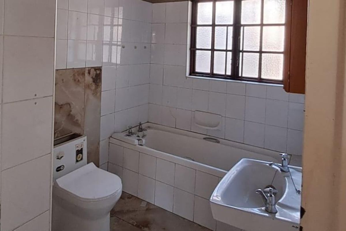 A dated bathroom featuring a bathtub, pedestal basin, and toilet with tiled walls, requiring renovation to update the finishes and fixtures.