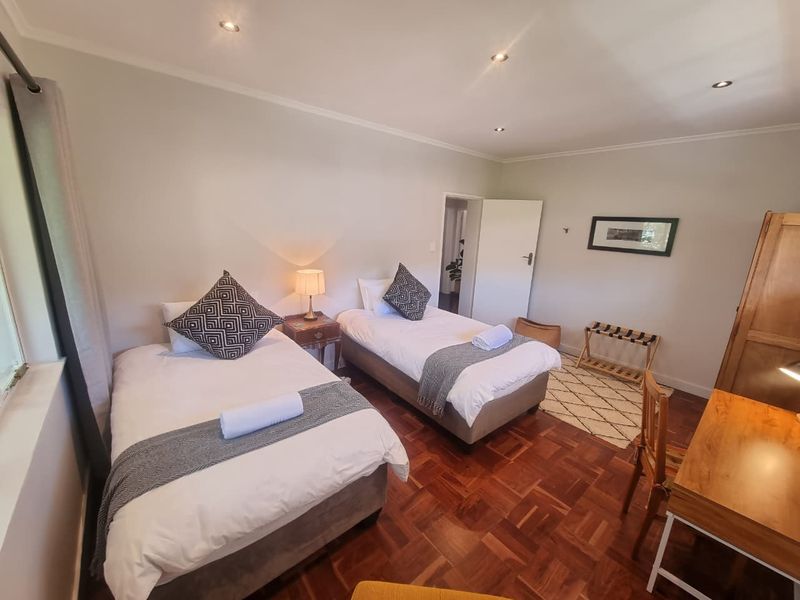 A well-maintained bedroom featuring classic parquet flooring, recessed ceiling lighting, and neutral wall finishes, providing a comfortable and functional living space.