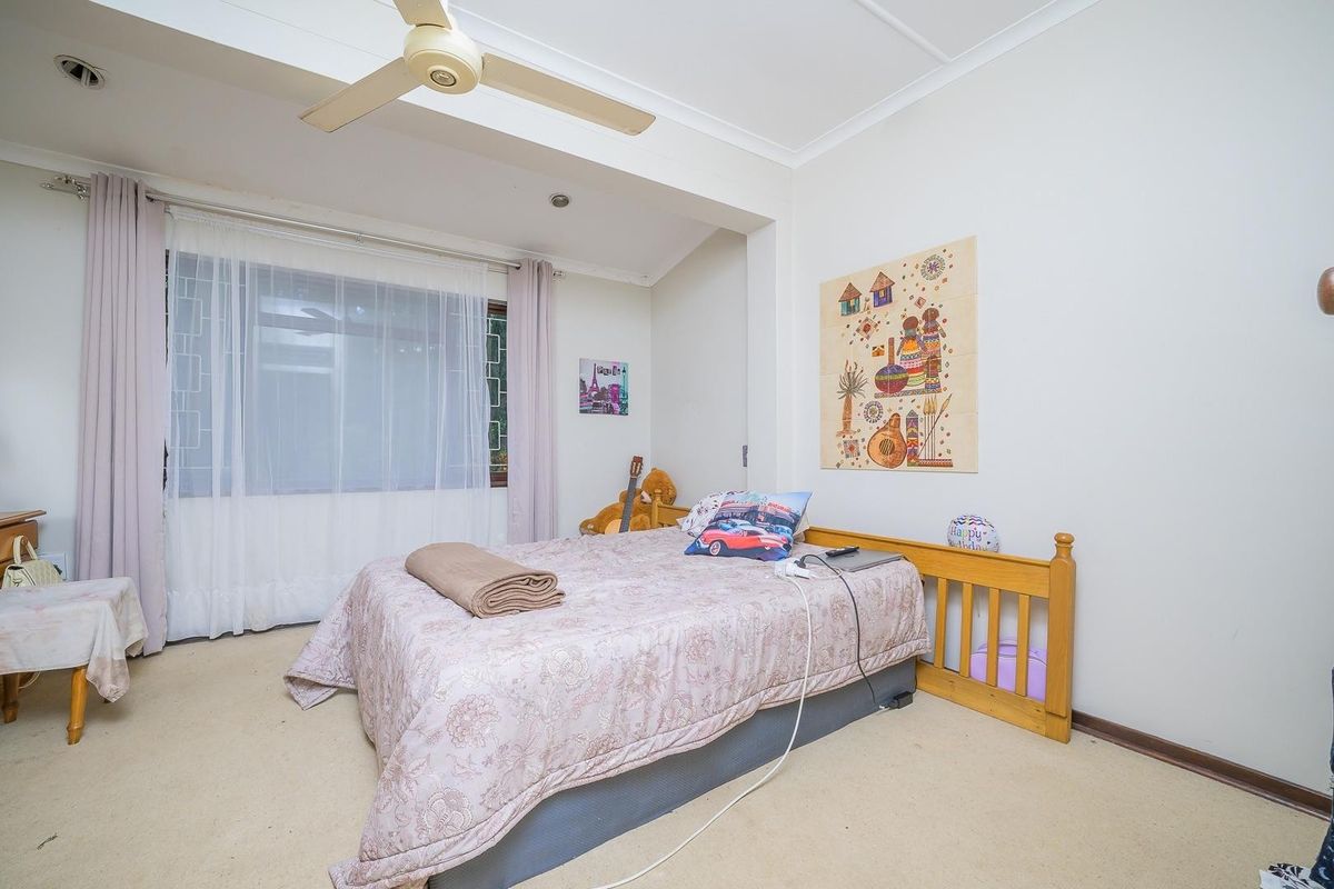 A well-lit bedroom featuring neutral carpet flooring, a ceiling fan, and large windows with curtain tracks, offering a comfortable and functional living space.