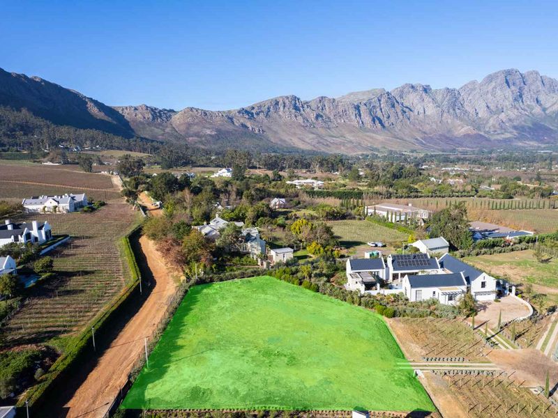 Aerial view of a vacant residential plot situated in a scenic estate with mountain views and surrounding vineyards.