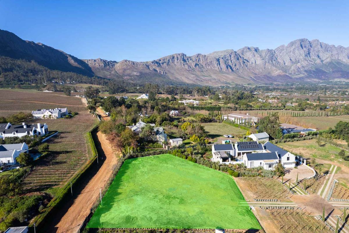 Aerial view of a vacant residential plot situated in a scenic estate with mountain views and surrounding vineyards.