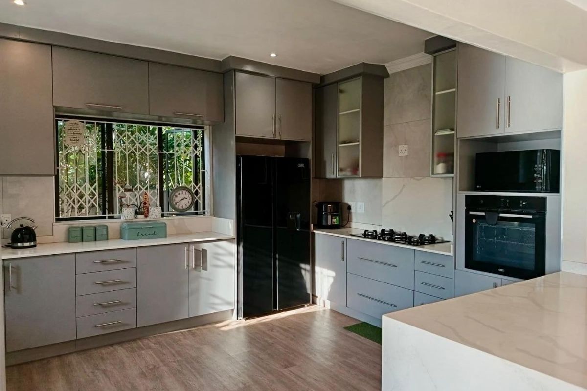 Modern kitchen featuring sleek grey cabinetry, stone countertops, built-in oven, gas hob, and integrated microwave, offering a clean and functional culinary space.