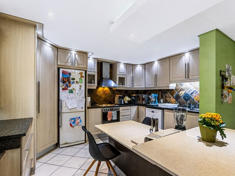 Functional kitchen featuring light wood cabinetry, stone countertops, a central island, and a tiled backsplash, offering ample storage and workspace.