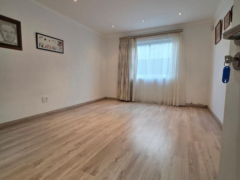 A bright, empty living room featuring modern laminate flooring and recessed downlighting, offering a clean and neutral space ready for personalization.