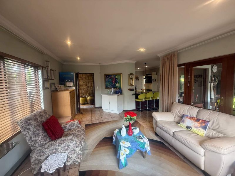 Open plan living area featuring tiled floors, recessed lighting, and a breakfast bar, with a view through to the kitchen and stone-accented hallway.