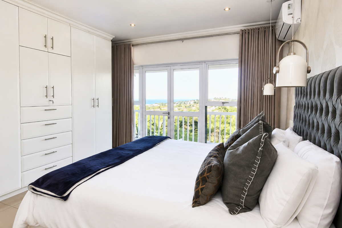 A well-appointed bedroom featuring extensive built-in cabinetry, air conditioning, and direct access to a balcony with scenic views.