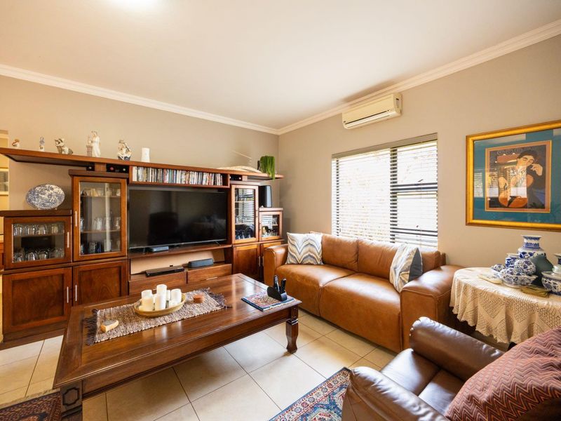 A comfortable living room featuring tiled flooring, crown molding, and a wall-mounted split-system air conditioning unit.