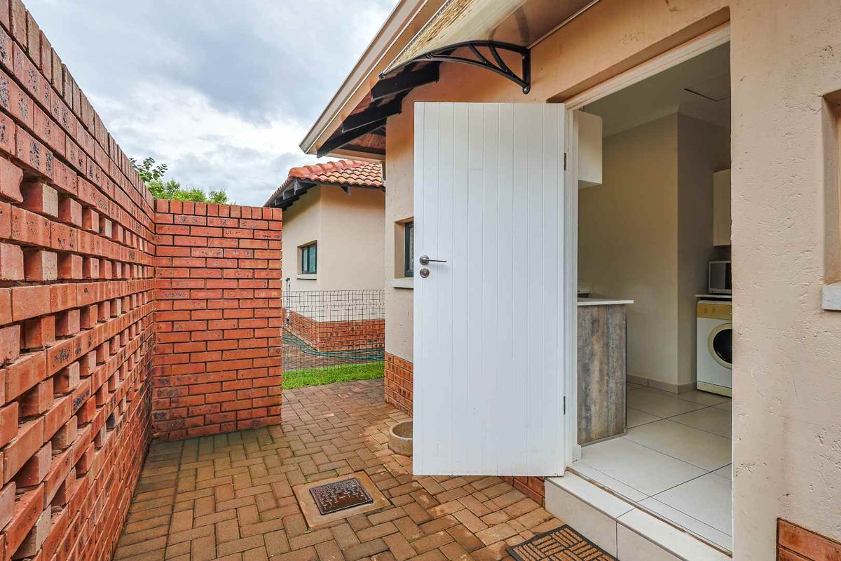A functional exterior laundry area featuring brick paving, a privacy brick wall, and direct access to the interior utility space.