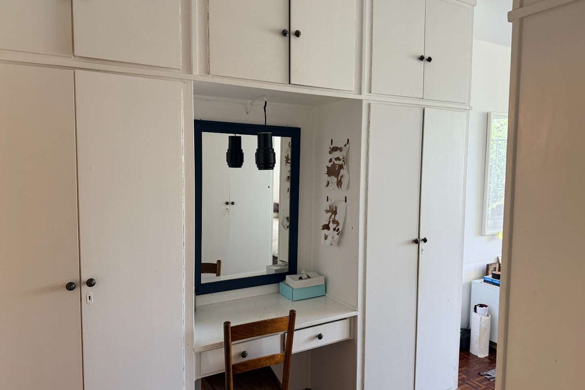 Bedroom featuring extensive built-in white cabinetry with an integrated vanity desk and classic parquet flooring.