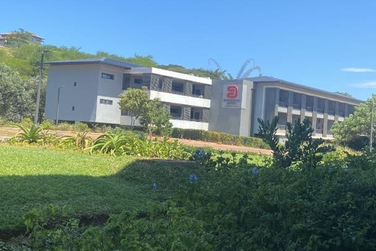 A view of the apartment complex exterior, featuring well-maintained landscaped grounds and modern building architecture under a clear blue sky.
