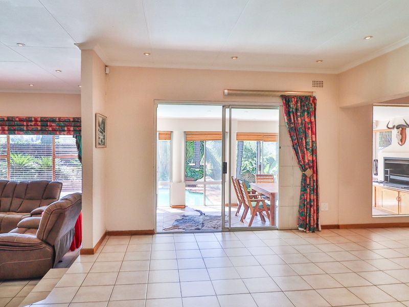 Spacious open-plan living area featuring tiled flooring, recessed lighting, and large sliding doors providing seamless access to the outdoor patio and pool area.