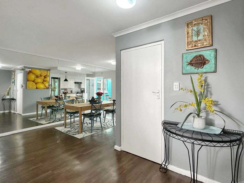 An open-plan living and dining area featuring laminate flooring, a large mirrored wall, and a view into the adjacent kitchen space.