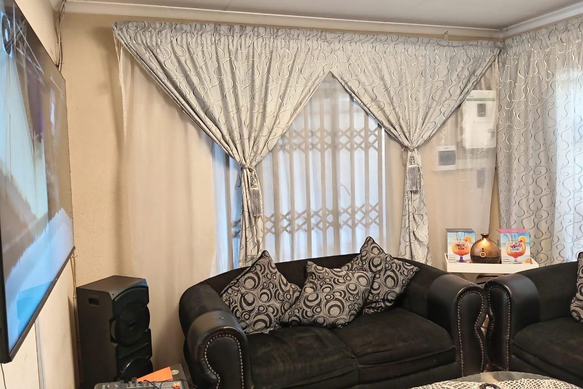 A living room featuring a security gate on the window and wall-mounted television setup.