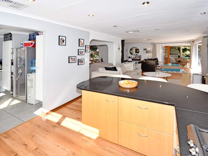 Spacious open-plan living area featuring a kitchen island with granite countertops, wood flooring, and seamless flow to the outdoor patio through sliding glass doors.