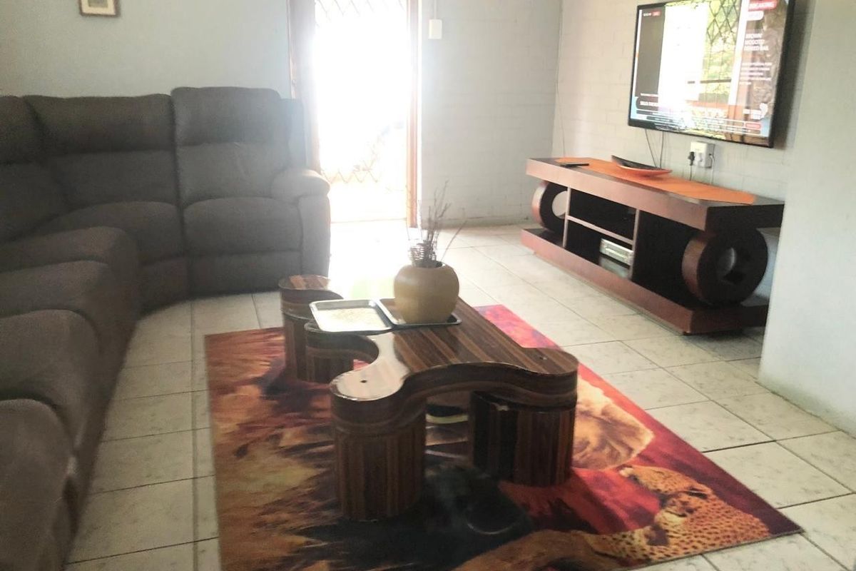 A living room area featuring tiled flooring and access to an exterior door with a security gate.