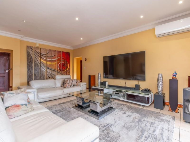 Spacious living room featuring tiled flooring, recessed downlighting, and a wall-mounted split-system air conditioner.