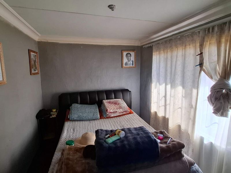 A compact bedroom featuring grey walls, cove cornicing, and a window with installed curtain rails.