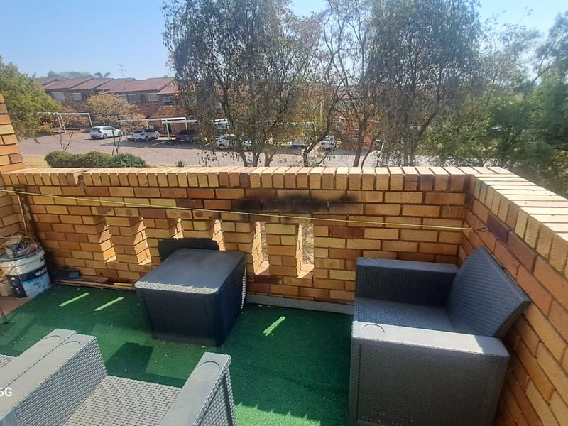 An outdoor balcony featuring a brick balustrade with visible soot staining, finished with artificial grass flooring.