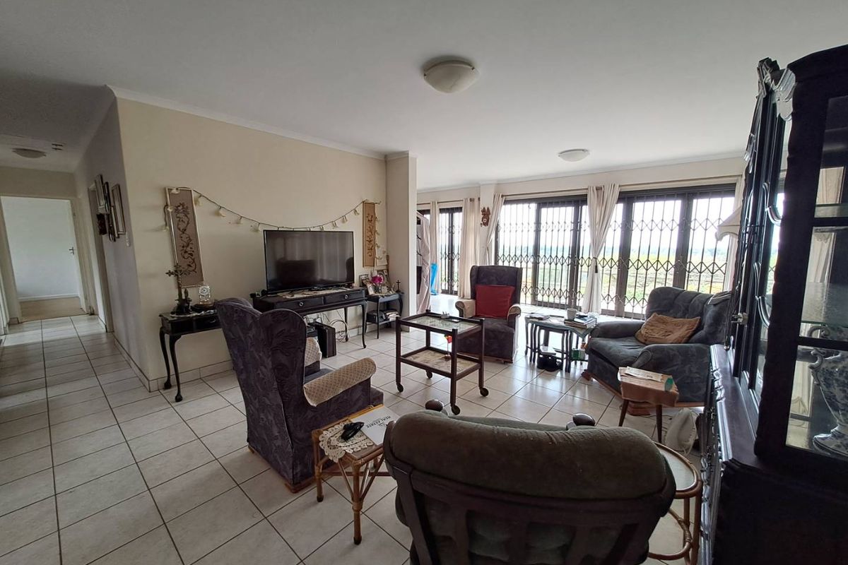 Spacious living area featuring ceramic floor tiles and large sliding glass doors with security gates, providing ample natural light and access to the exterior.