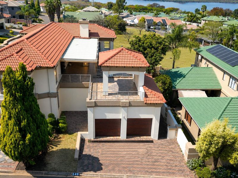 Aerial view of a residential property featuring a double garage, tiled roof, and an elevated terrace area within a suburban estate.
