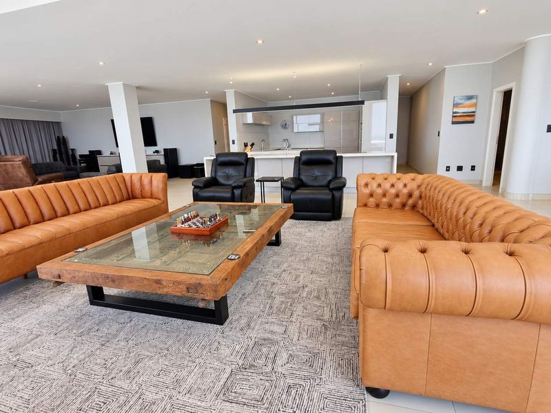 Spacious open-plan living area featuring a modern kitchen with a central island, recessed lighting, and neutral tiled flooring throughout.
