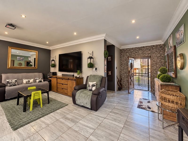 Spacious living room featuring tiled flooring, recessed downlighting, crown molding, and a decorative stone-clad feature wall near the entrance.
