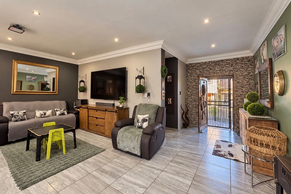 Spacious living room featuring tiled flooring, recessed downlighting, crown molding, and a decorative stone-clad feature wall near the entrance.