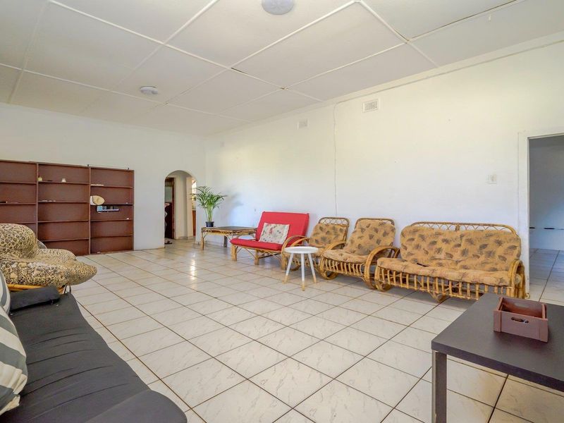 Spacious living area featuring tiled flooring, a built-in shelving unit, and an archway leading to adjacent rooms.