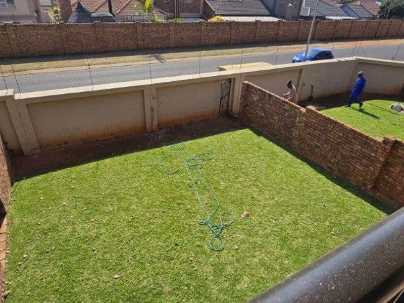A private rear garden featuring a lawn area enclosed by brick boundary walls with integrated electric fencing.